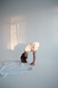Woman bending over in a minimalistic room with soft lighting, conveying solitude.