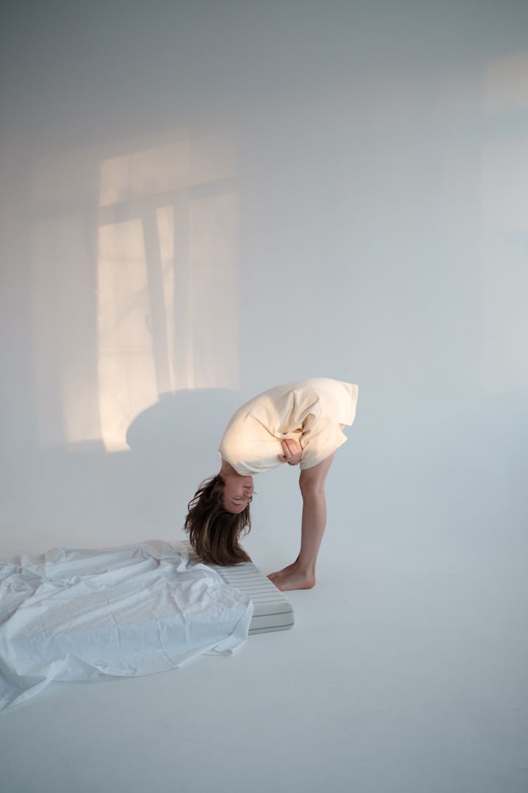 Young Woman Bending Forward Near Mattress