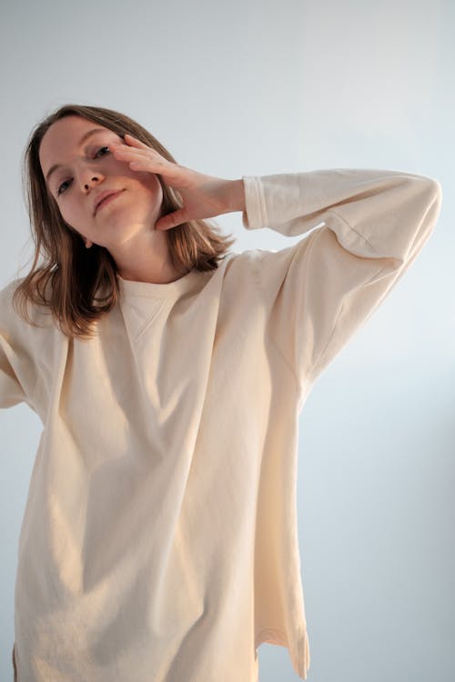 Young woman in sweatshirt touching face