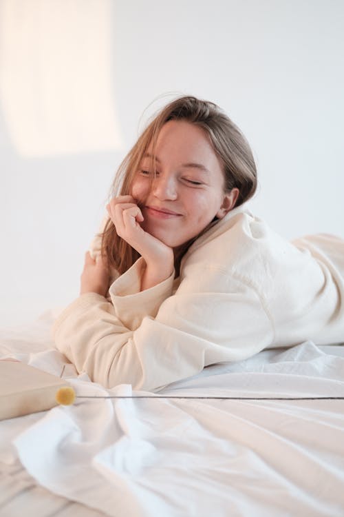 Optimistic female resting on bed with closed eyes