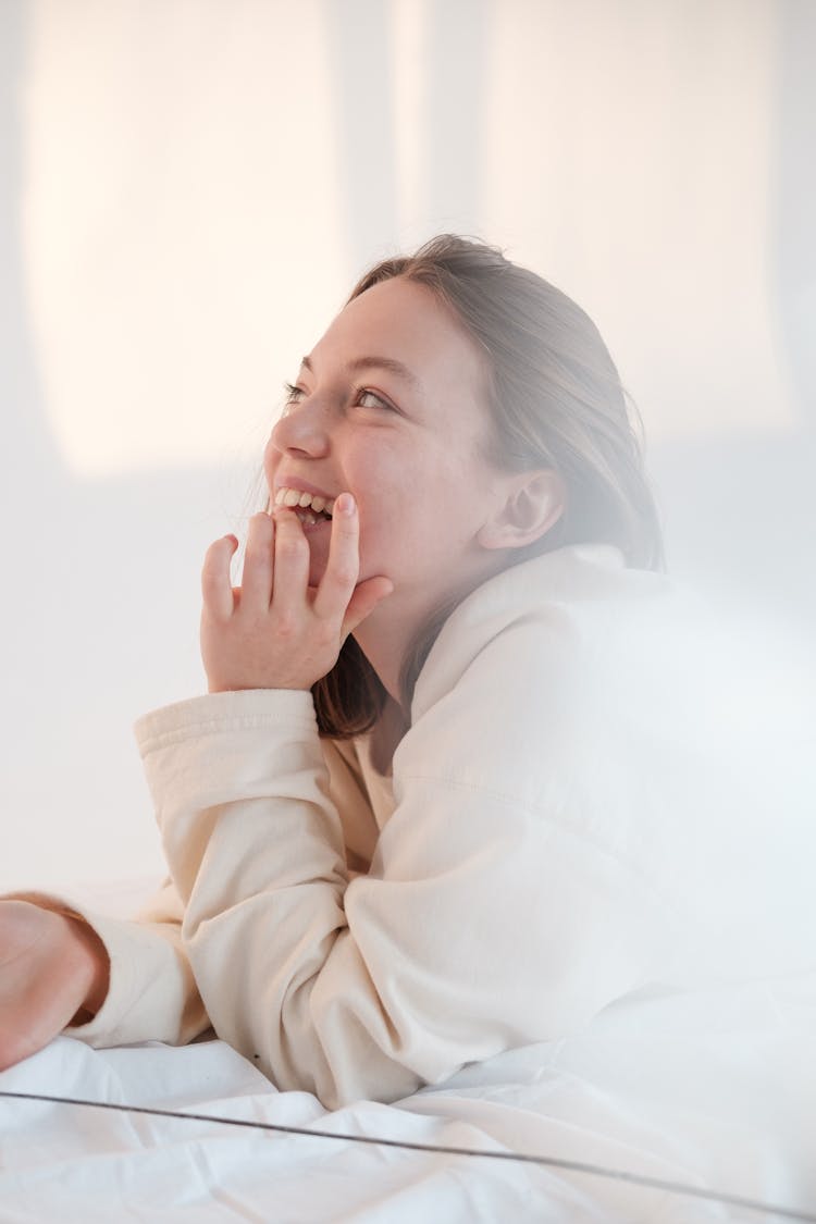 Happy Woman Biting Nails While Resting On Bed