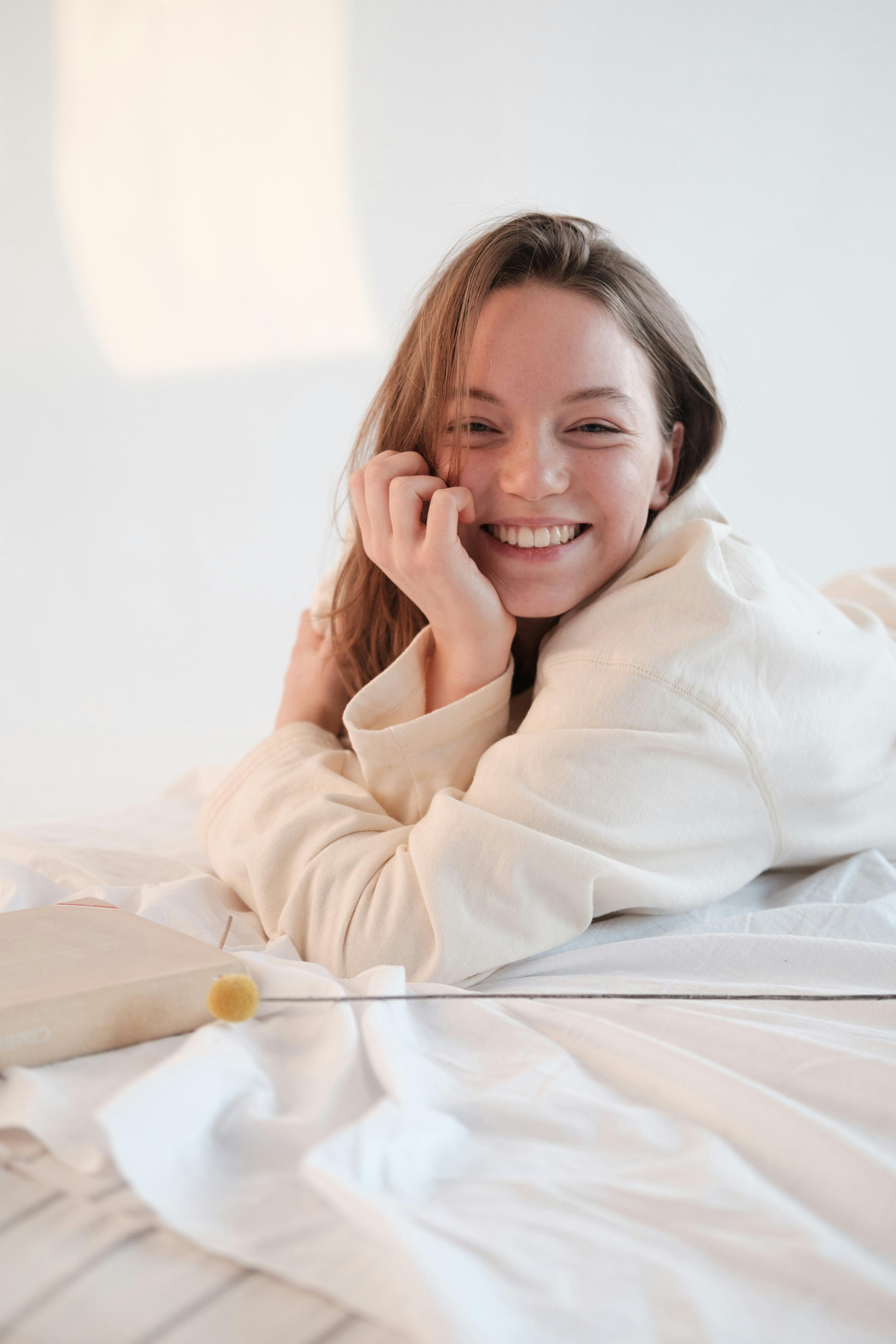 optimistic female chilling on bed and smiling