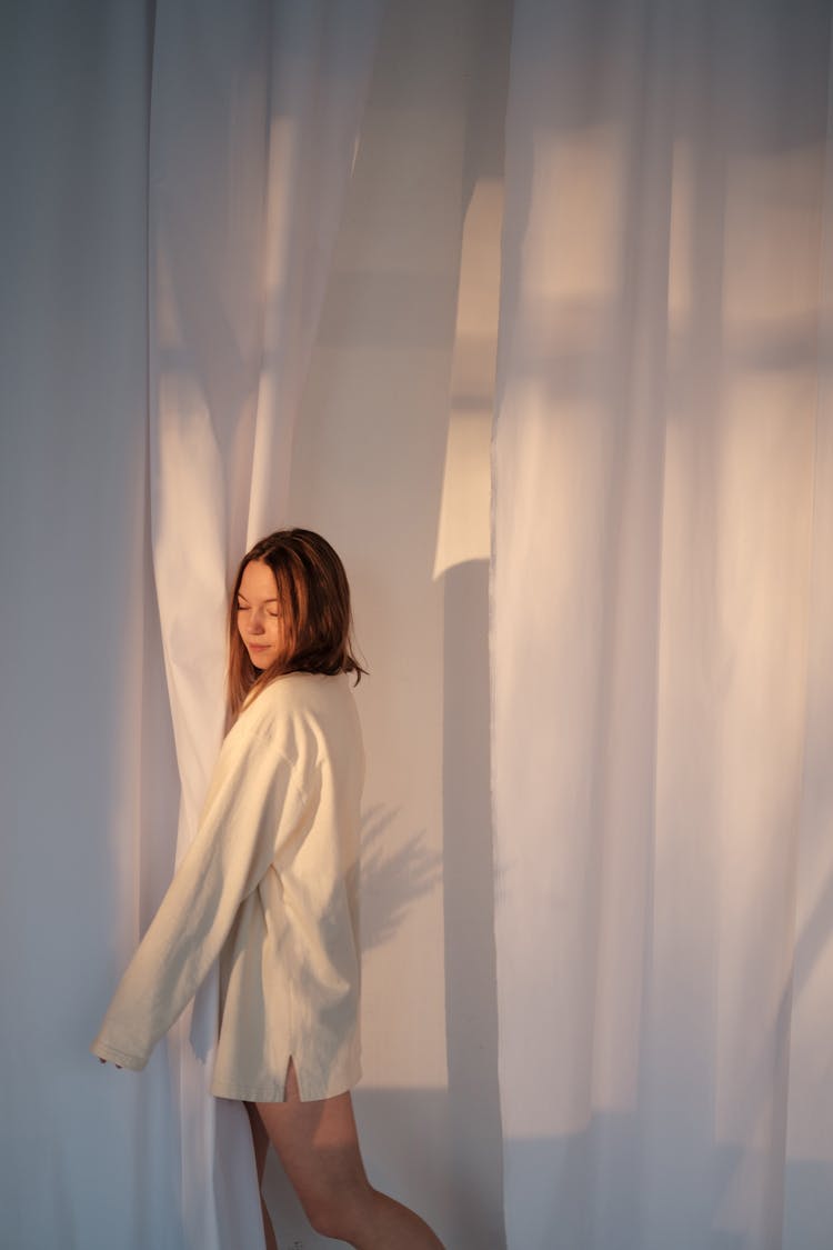 Young Woman Embracing White Curtain