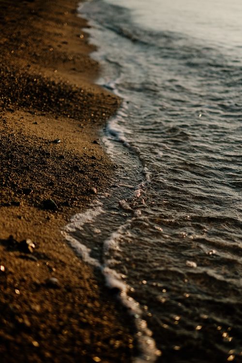 Free Tranquil waves gently lapping on a sandy beach during golden hour, evoking calm and relaxation. Stock Photo