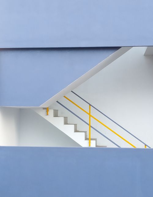 Free A minimalist staircase with blue walls and yellow handrails in a modern architectural building. Stock Photo