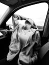 Grayscale Photo of a Woman in Zip Up Jacket Sitting Inside a Car