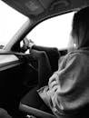 Grayscale Photo of Woman Resting Her Legs on Car Window