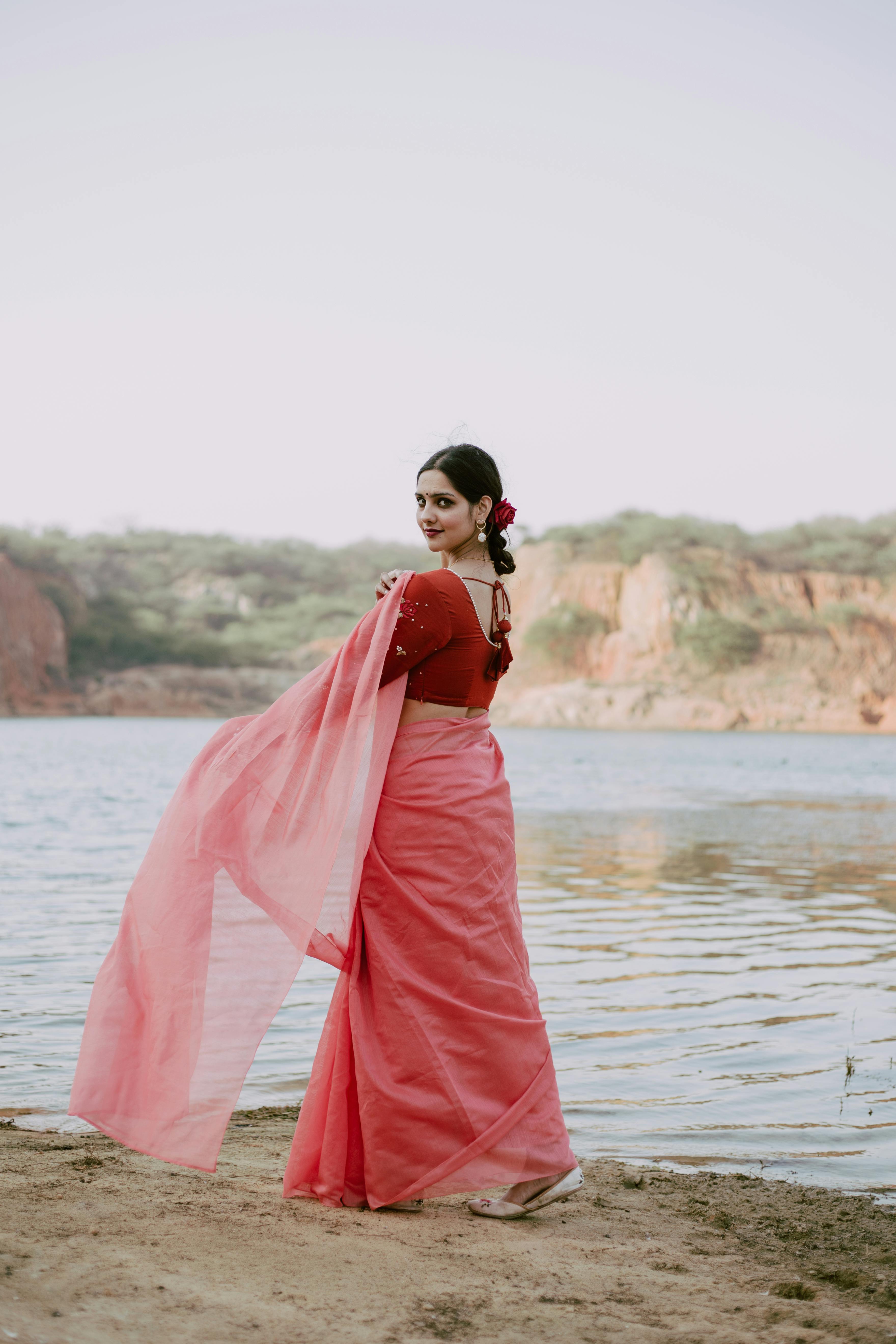 Ethnic female in traditional sari dress on shore of lake · Free Stock Photo