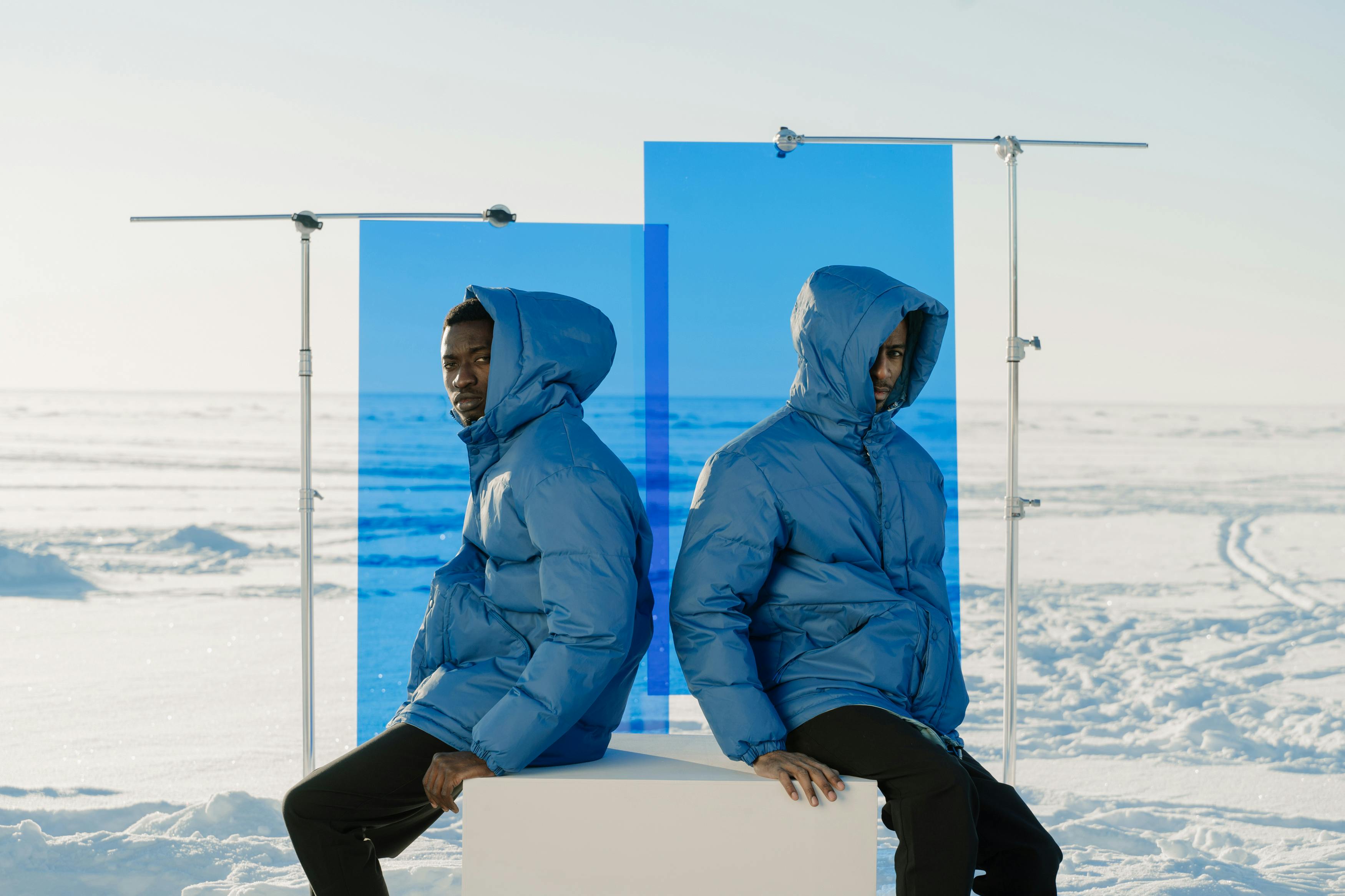 Two men in blue jackets posing in a snowy winter scene. Fashion photography.