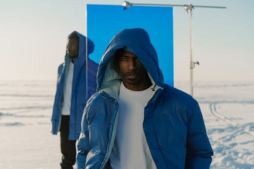 Close-up Shot of Men in Blue Winter Jacket Standing on a Snow Covered Ground while Posing at the Camera