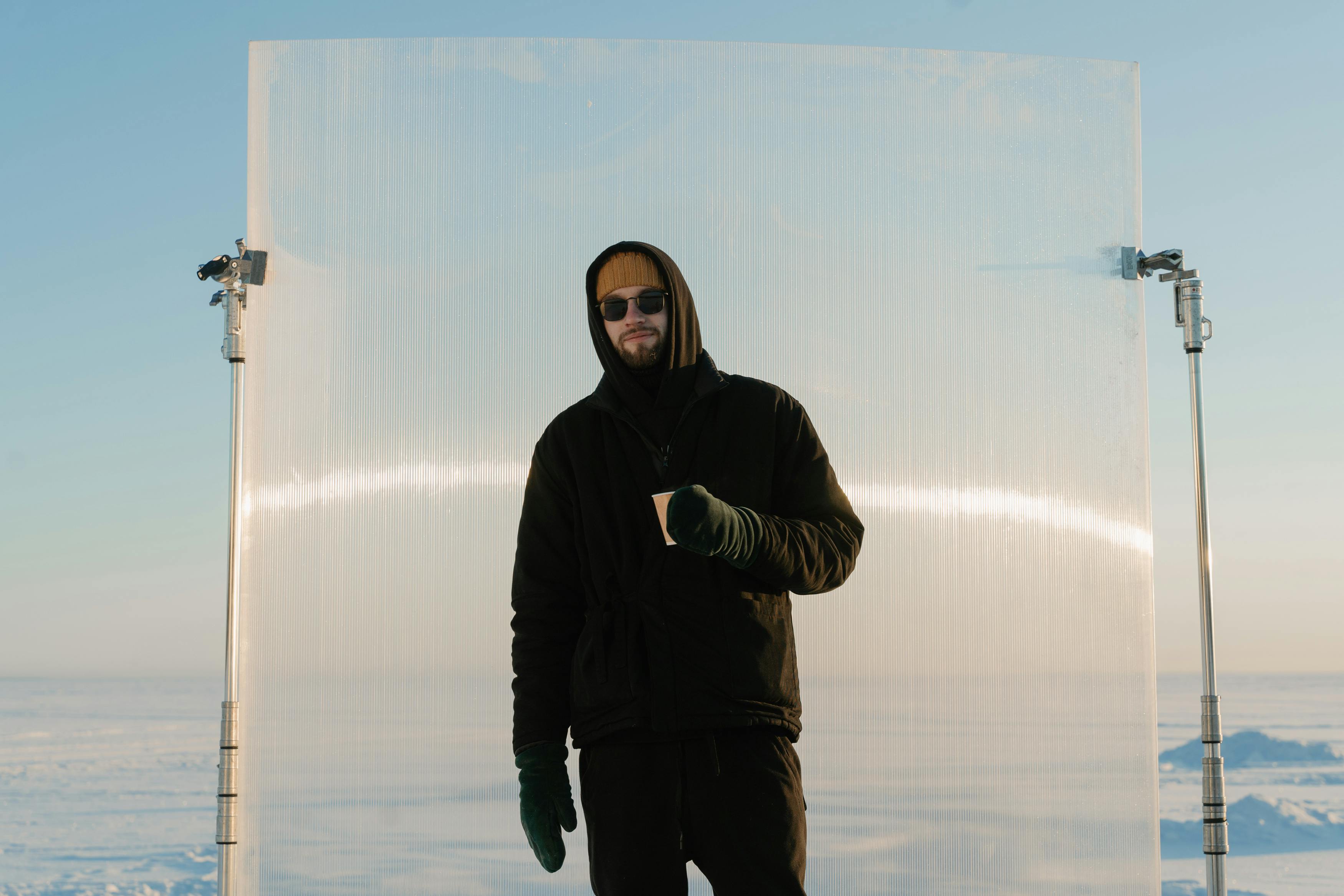 man in black hoodie standing in front of a backdrop on a c stand