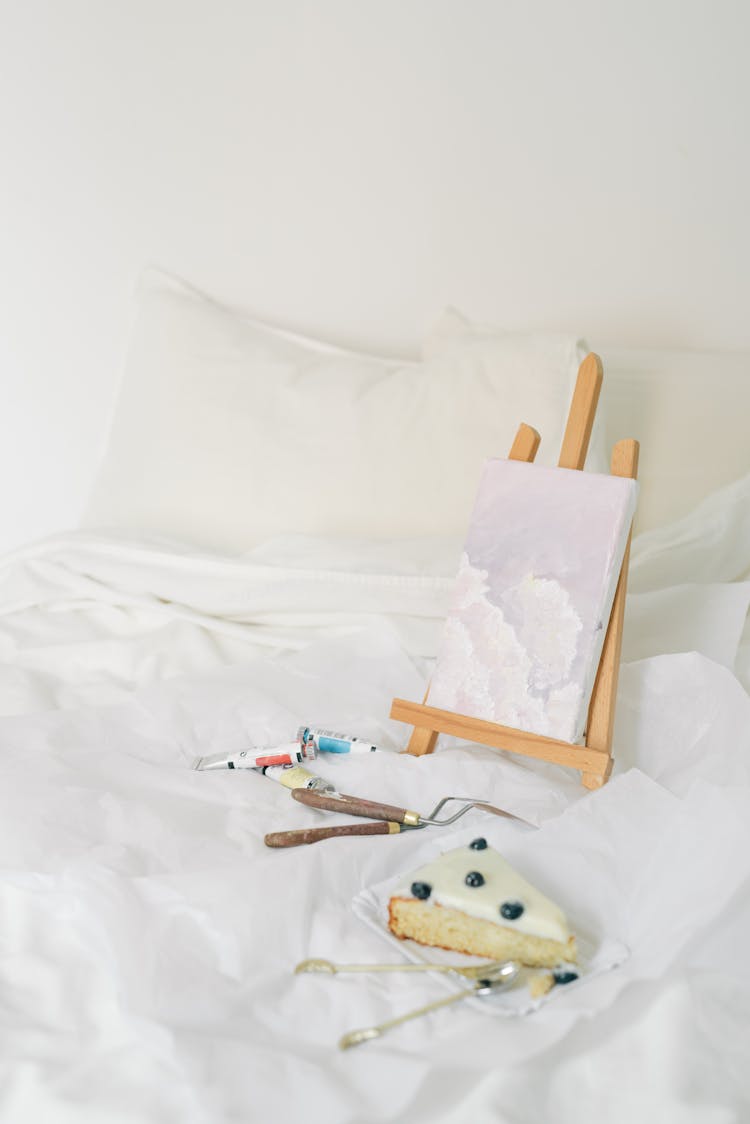 Painting Materials And A Plate Of Sliced Cake On A White Surface