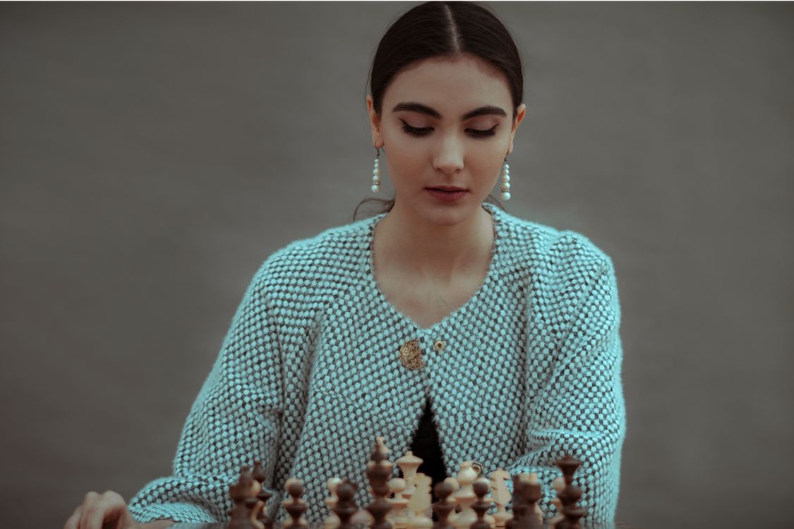Ethnic woman thinking on chess move during game · Free Stock Photo