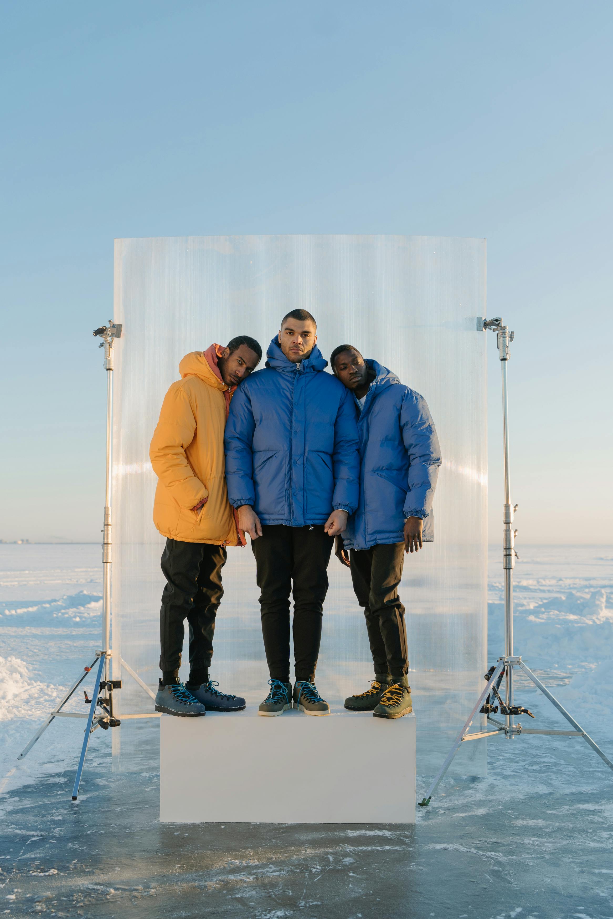 men in puffer jacket standing on a platform on a snow covered place