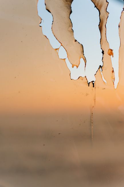 Close-up of a burned, peeling surface with soft orange hues and clear sky for creative backgrounds.