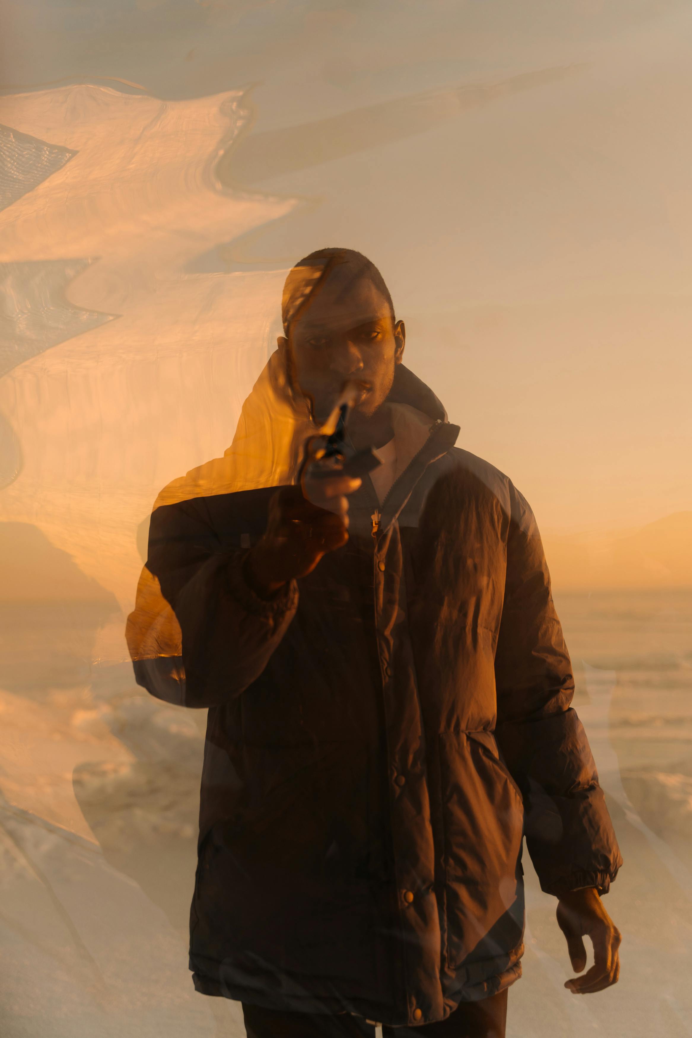 Moody portrait of a man in a jacket at sunset with reflective artistic effects.