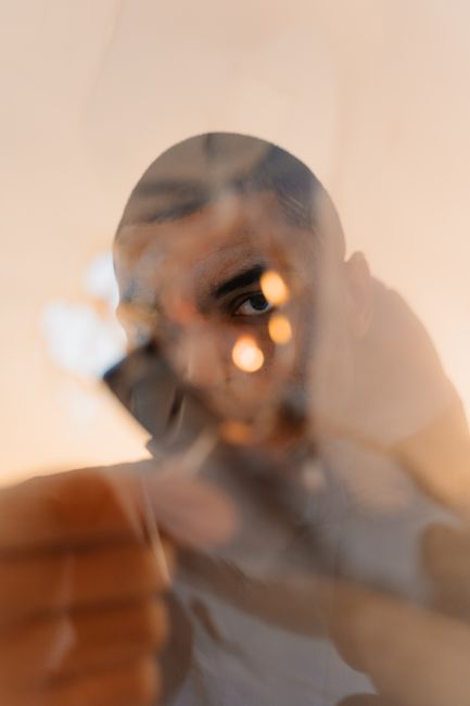 Abstract portrait of a man with short hair, creatively framed by a blurred glass reflection.