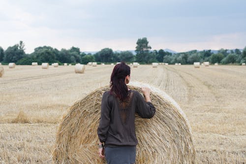 Woman Standing in Front of Hay