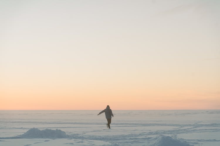 Person In Jacket Running On Snow Covered Ground