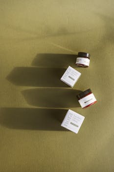Top view of skincare products casting long shadows on an olive green background.