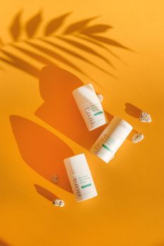 Flat lay of skincare products with shadows on a vibrant orange backdrop.