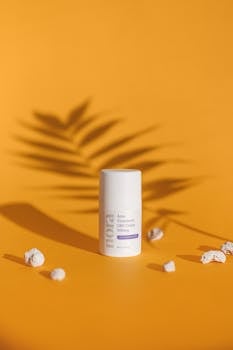 Acne treatment cream with palm leaf shadow on vibrant orange background.