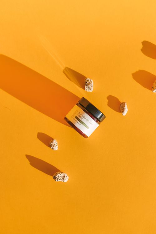 Free Amber jar of beauty product with shadow and stones on a bright orange background. Stock Photo