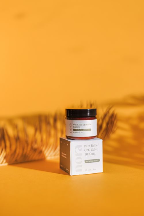 Free Elegant CBD salve jar with natural leaf shadow on a warm backdrop, perfect for holistic health themes. Stock Photo