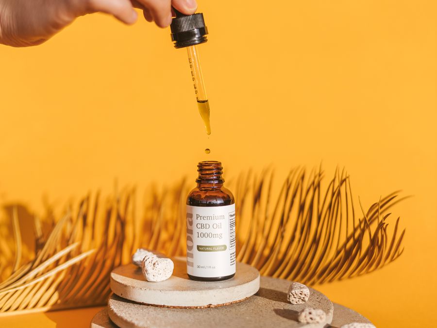 Dropper bottle of oil on an orange background