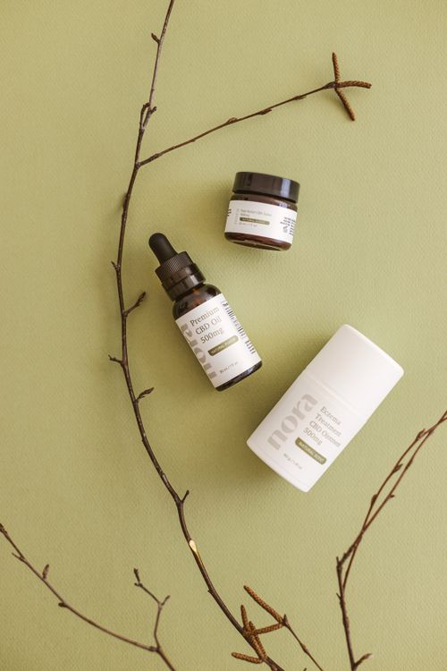 Free Flat lay of CBD skincare products with branches on a green background, highlighting natural ingredients. Stock Photo