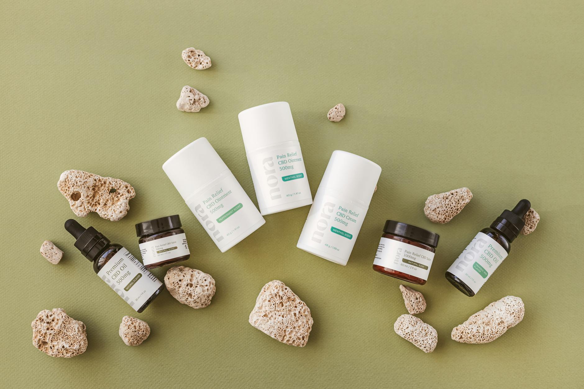 Array of organic CBD skincare products displayed with natural stones on a green background.