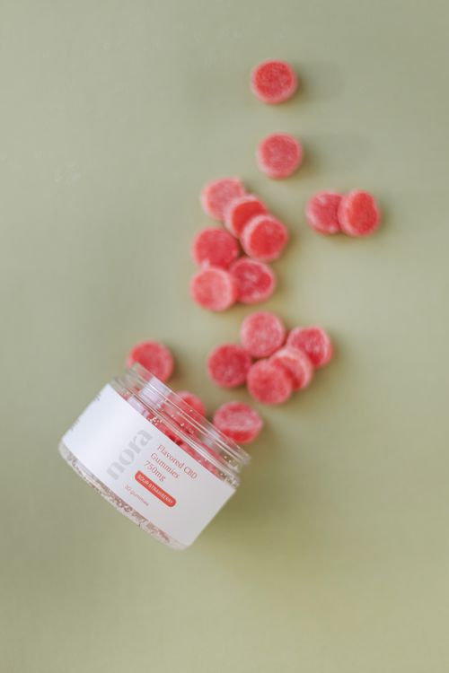Free An open glass bottle spilling pink gummies on a green backdrop. Stock Photo