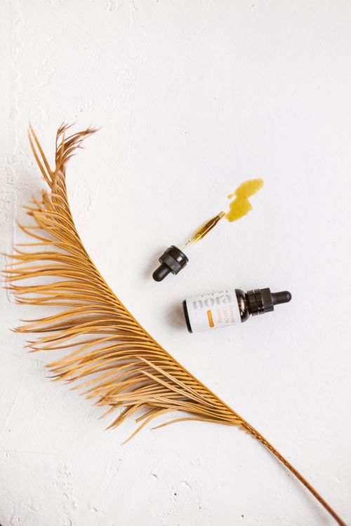 Free A close-up of a CBD serum dropper with oil spill and palm leaf on a white background, showcasing clean beauty. Stock Photo