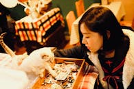 一名年轻女子在舒适的环境中，与一只猫在铺满彩色织物的桌子上互动