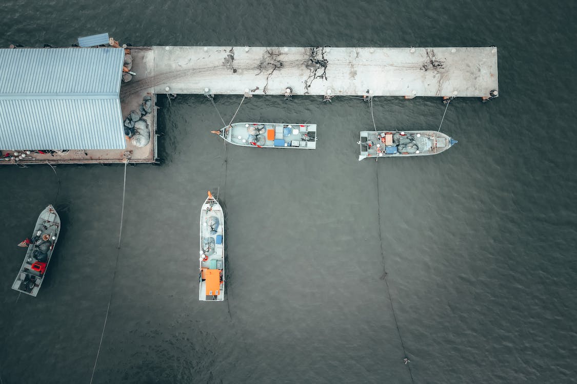 Aerial view of barges with heavy cargo moored on dock of rippling river