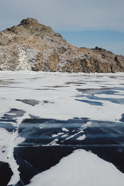 Free A Rocky Mountain Above the Frozen Lake Stock Photo