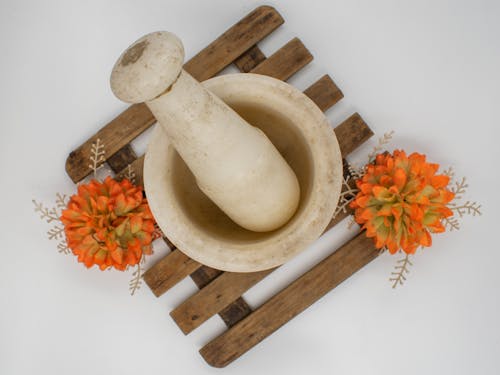 Free White Pestle on Brown Wooden Board with Orange Flowers Stock Photo