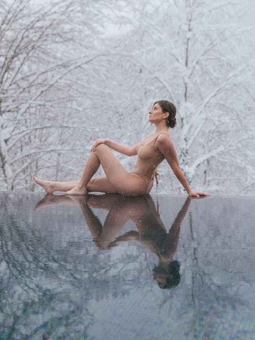 Woman in Swimsuit Sitting on Poolside in Winter
