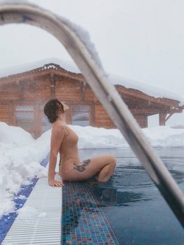 A woman enjoying a serene winter moment by a snowy poolside.
