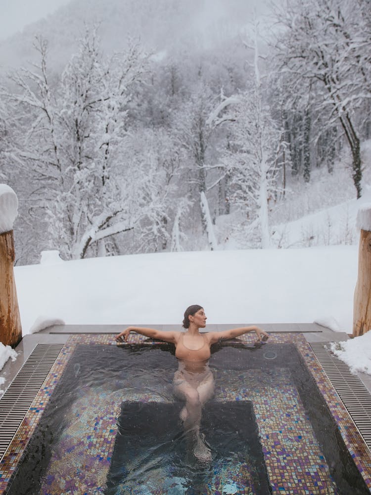 Woman In A Hot Tub Near A Snow Covered Forest