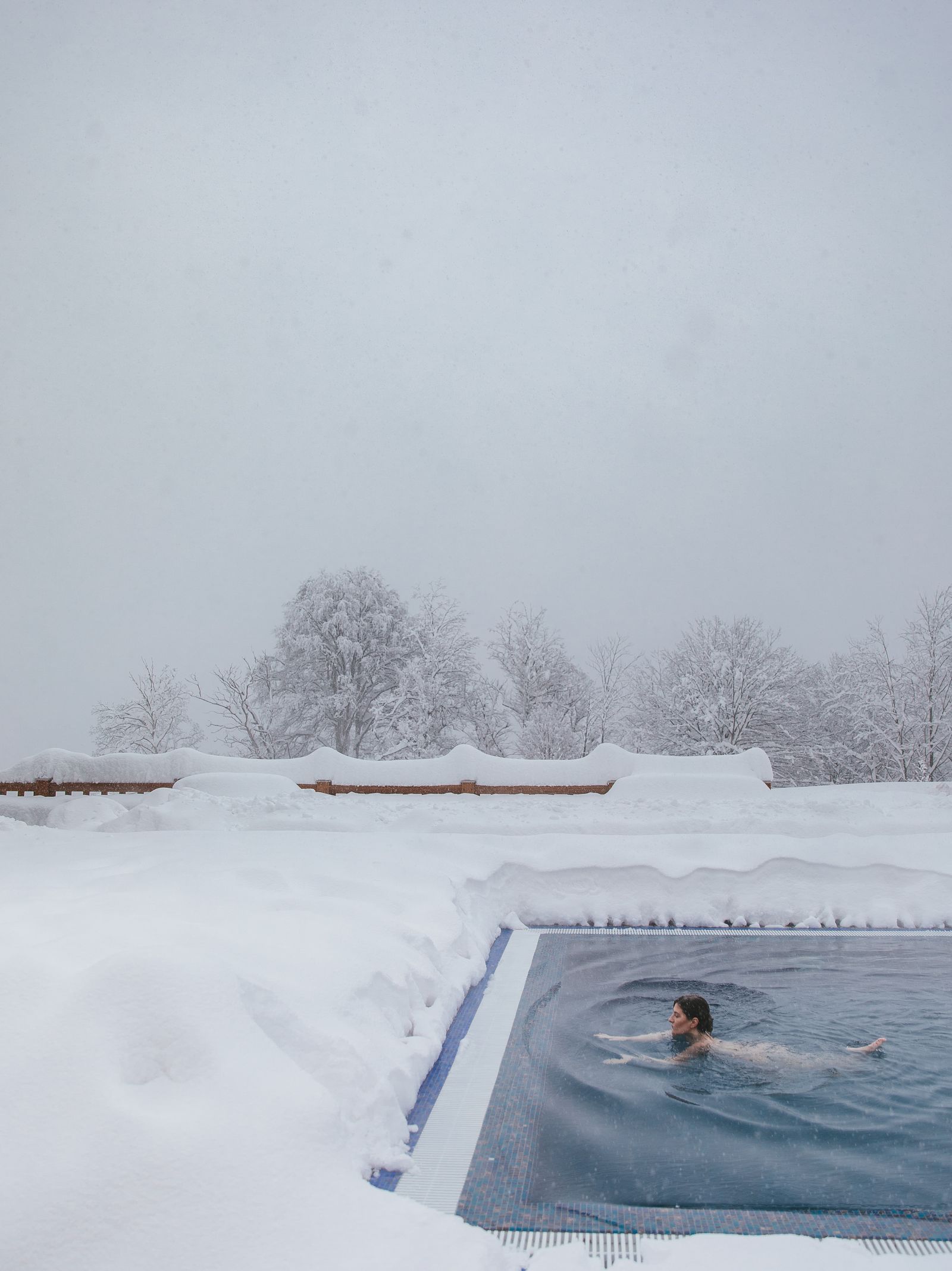 A swimmer doing lengths in an outdoor pool in the snow
