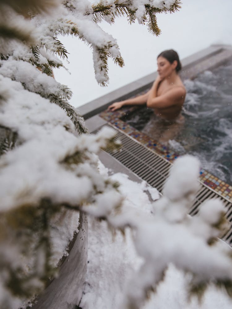 A Woman Soaking On A Jacuzzi Near Snow Covered Tree