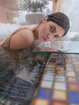 An elegant portrait of a woman in a snow-covered poolside setting, showcasing winter beauty.
