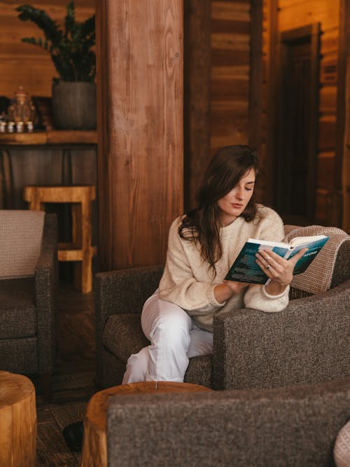 Woman Wearing a Sweater Reading a Book