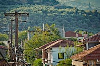 郁郁葱葱的丘陵景观中，乡村风光与瓷砖屋顶和电力线相映成趣