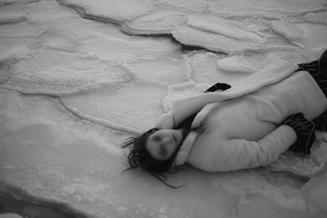 A Woman Lying Down on the Snow Covered Ground
