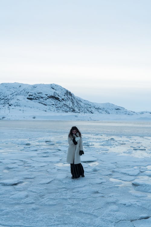 A Woman in Fur Coat Standing on a Snow-Covered Field