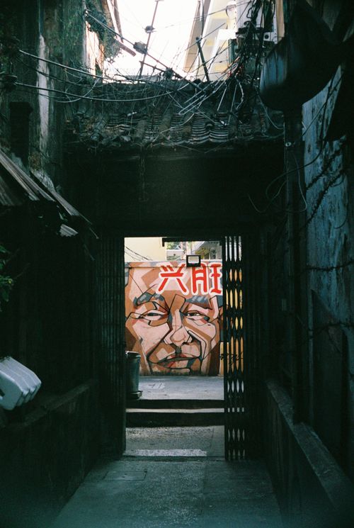 Free An urban alleyway featuring a vibrant mural of a face, showcasing street art. Stock Photo