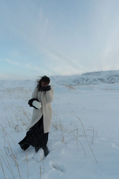 Woman in a long coat standing in a vast snowy landscape — photo by Yaroslav Shuraev on Pexels