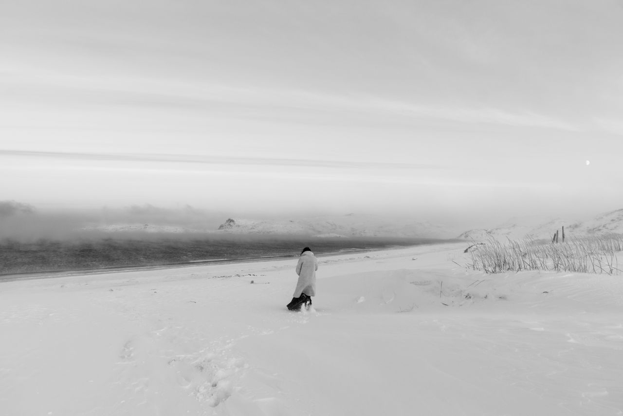 Black-and-white photo of a person walking through deep snow